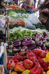 Customers choose the product in the vegetable market, on the counter pepper, eggplant and many other vegetables.