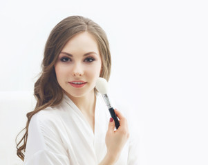 Beauty portrait of young and attractive woman with makeup brush. Make-up and cosmetics concept.