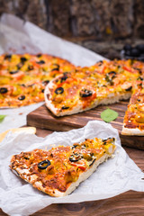 Cut pizza with chicken, tomatoes, cheese and black olives