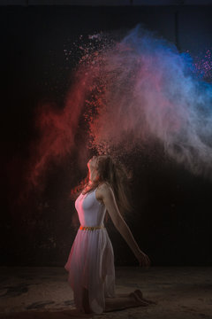 Beautiful slim female dancer in studio during Powder Photo Shoot with colored light