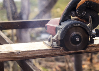 male hands with circular saw while workimg with wood