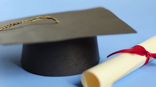 Education and learning concept. Isolated graduation cap and diploma dolly shot