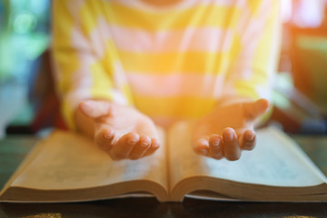 woman praying on holy bible in the morning. teenager hand with Bible praying,Hands folded in prayer on a Holy Bible in church concept for faith, spirituality and religion. victory concept for god.