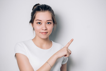 Cute young woman points a finger away. Presenting your product. Expressive facial expressions