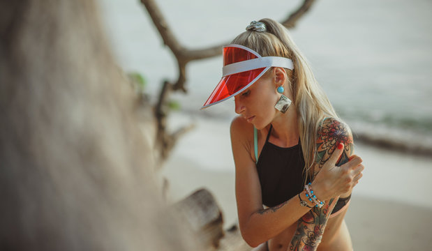 Portrait of a beautiful girl in a red visor closeup. Wearing Large turquoise earrings. Holiday in Thailand On the background of evening beach