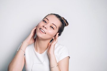 Beautiful young woman in headphones listening to music and singing on white background