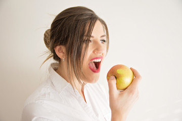 Beautiful woman with pearly white and healthy teeth eating apple