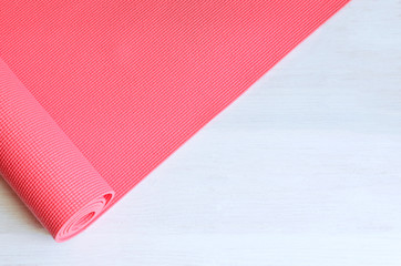 Open pink exercise mat on white wooden background.  Concept for practice yoga, pilates or any ...