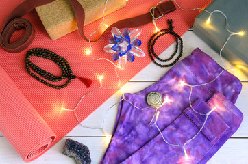Yogi accessories, yoga mat, yoga pants, strap and block, mala beads, ayurveda solid perfume, healing Crystal with christmas garland.  Yoga Christmas gift background.