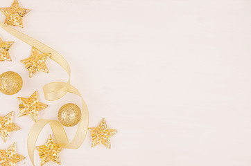 Christmas tree of gold stars, balls, curl ribbons on soft white wood board, top view, copy space, half.