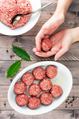 Female hands prepare meatballs on the wooden table