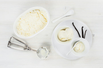 Two portions of vanilla ice-cream in the white plates on the wooden table