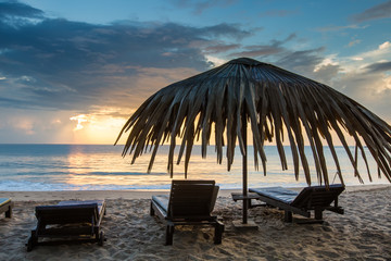 Sun loungers with umbrella on the beach, sunrise