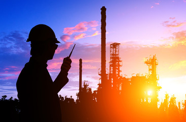 Silhouette of engineer and foreman working at petrochemical oil refinery in sunset