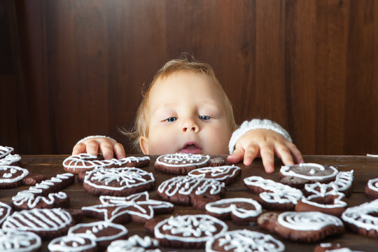 Small boy tries to grab traditional homemade Christmas ginger and chocolate cookie decorated with white sugar painting