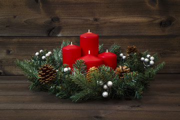 Decorated Advent wreath with four red candles on a wooden background