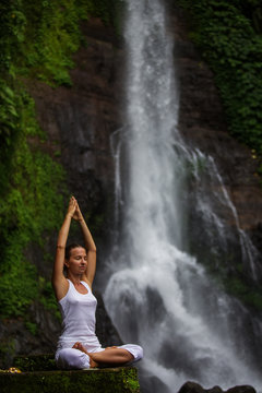 Woman practices yoga at Gitgit waterfall on Bali in indonesia