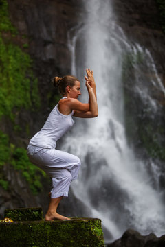 Woman practices yoga at Gitgit waterfall on Bali in indonesia