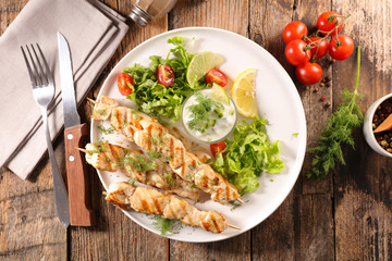 grilled chicken skewer with salad and sauce
