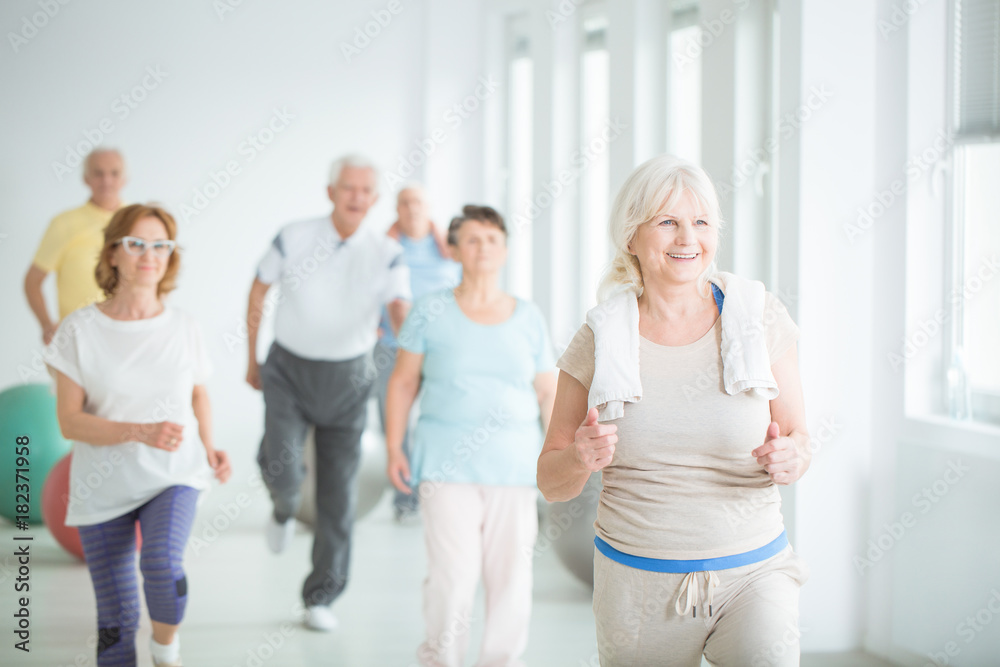 Wall mural smiling senior trainer showing exercise