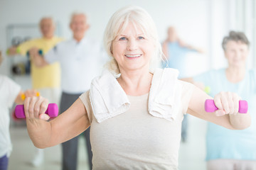 Fototapeta premium Elderly woman exercising with dumbbells
