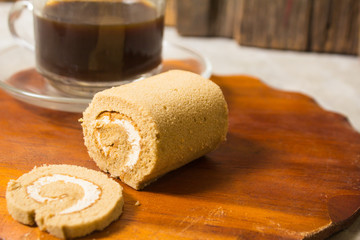 Roll small cake smells coffee with cream. Platters of brown and black coffee, ideal for breakfast, snacks and coffee breaks
