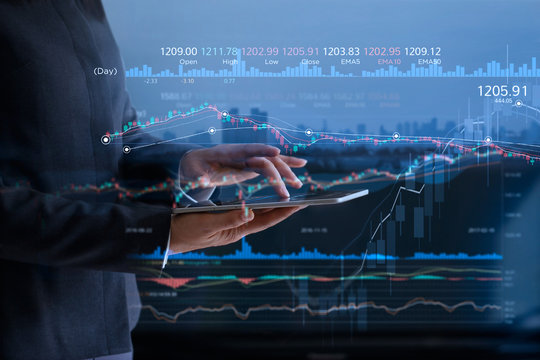 Business people checking stock market on tablet and analysing financial data on a screen with graph and candlestick chart on LED monitor virtual on the city background