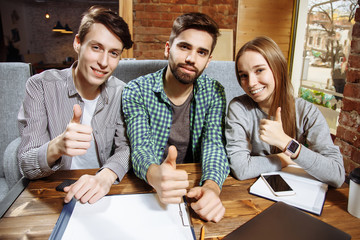 Group of happy successful young people showing thumb up.