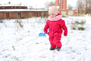 little girl in warm overalls playing outdoors in winter