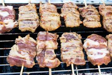 Grilled pork with bamboo sticks skewer on roaster background