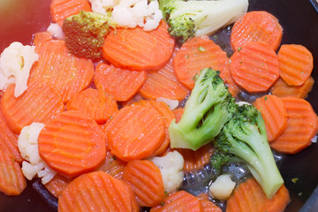 Fried vegetables in a frying pan. Carrots, broccoli and cauliflower are fried