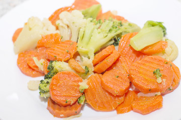 Fried vegetables on a white plate. Carrots, broccoli and cauliflower