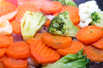 Fried vegetables in a frying pan. Carrots, broccoli and cauliflower are fried