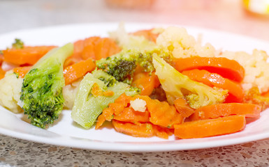 Fried vegetables on a white plate. Carrots, broccoli and cauliflower