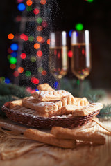 homemade cookies, glasses with champagne and a New Year tree on a festive table on a background of multi-colored New Year's lights