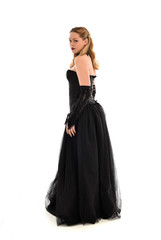 Naklejka premium full length portrait of a blonde girl wearing black gothic gown. standing pose, isolated on white background.