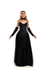 Fototapeta premium full length portrait of a blonde girl wearing black gothic gown. standing pose, isolated on white background.
