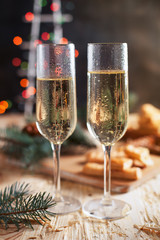 glasses with champagne, biscuits, a Christmas tree and New Year's lights on a New Year's festive table