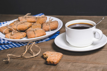Black coffee in a white cup on a blue napkin and homemade cookies.