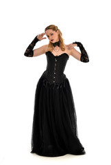 Fototapeta premium full length portrait of a blonde girl wearing black gothic gown. standing pose, isolated on white background.