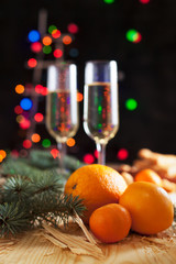 Fototapeta na wymiar glasses with champagne, mandarins, biscuits, a Christmas tree and New Year's lights on a New Year's festive table