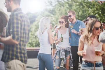 Group of friends talking and drinking while standing at outdoor party