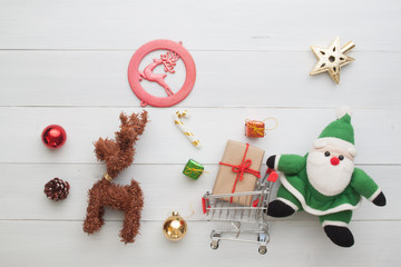 Creative flat lay of Christmas ornaments and gift boxes in shopping cart with Santa Claus, Christmas online shopping