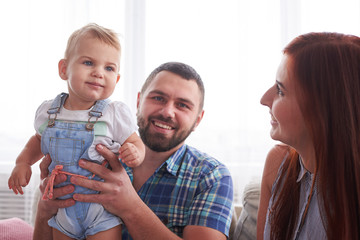 Young couple with liitle daughter relaxing on couch