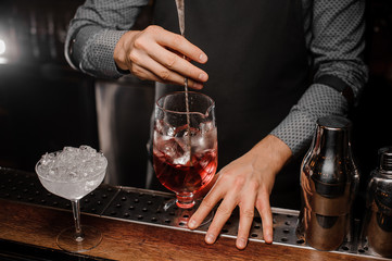 Fototapeta na wymiar Barman s hand stirring an alcoholic cocktail with ice