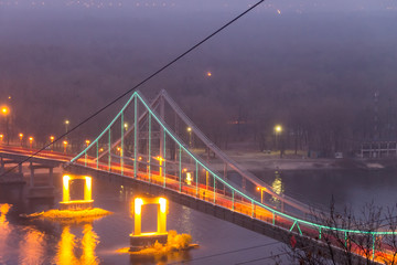 View on the pedestrian bridge across the Dnieper river at night. Kiev city, Ukraine