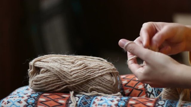 Close up panorama of the hands of a young woman knitting gloves with yarn