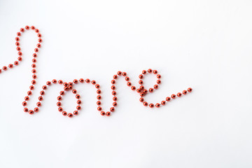 The word LOVE - declaration of written with red beads isolated on white background