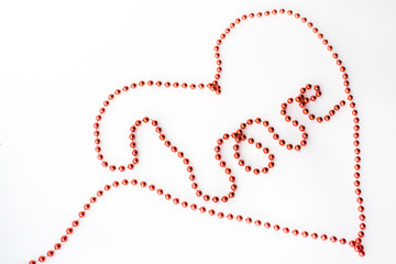 The word LOVE and symbol heart- declaration of written with red beads isolated on white background