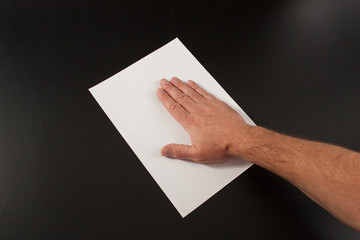 Male hands with paper on a black background. Studio